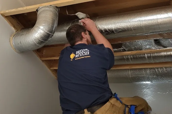 Certified HVAC technician professionally installing ductwork for an Energy Recovery Ventilator system