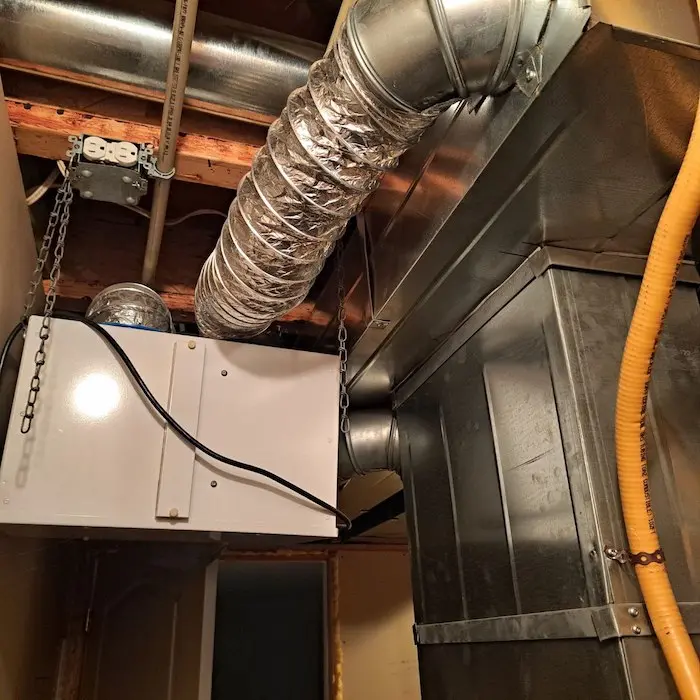 Échangeur d'air résidentiel moderne installé dans un sous-sol avec réseau de conduits