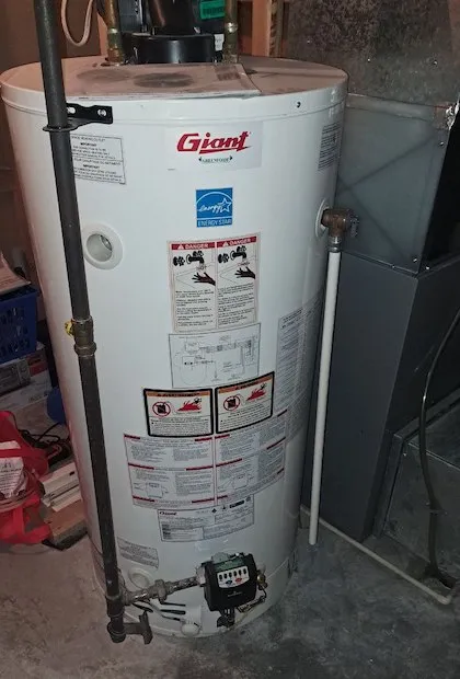 Un grand chauffe-eau au gaz de marque « Giant » dans un sous-sol, montrant des étiquettes de sécurité, un logo Energy Star et une soupape de commande de gaz au bas.